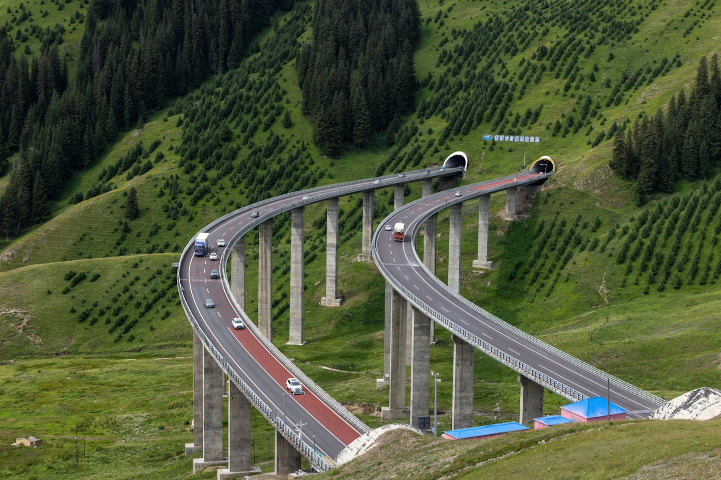 Moderni ponti autostradali si snodano attraverso un paesaggio montano verdeggiante.