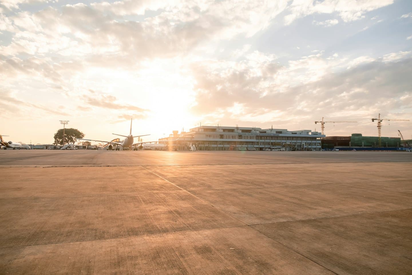 Aerei parcheggiati al terminal dell'aeroporto all'alba con gru edili.